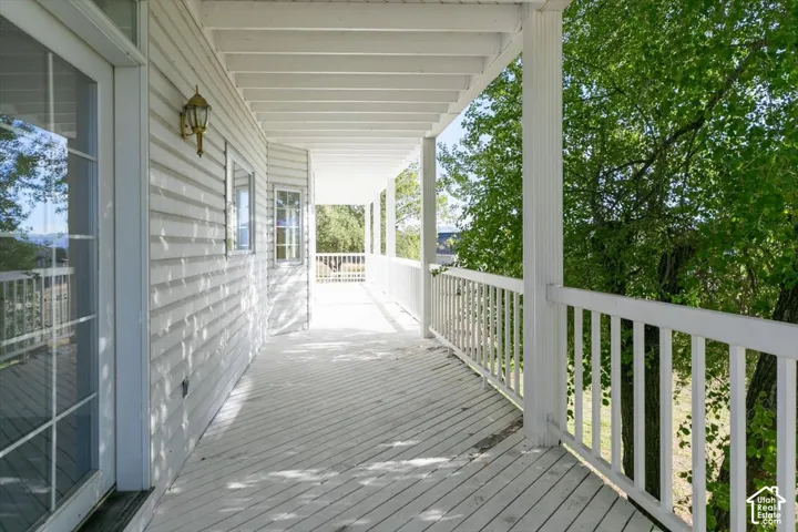 Covered porch with white wood plank flooring, white wood siding, and white railings