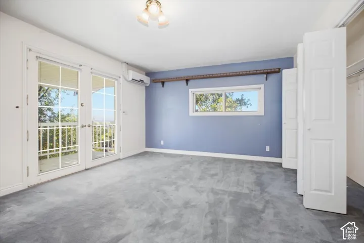 French doors opening to an outdoor area, split-unit air conditioning system, a window with exterior scenery, and built-in closet storage with bi-fold doors