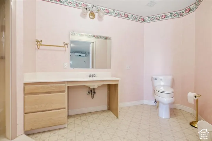 Vanity with integrated sink, wood-finish cabinetry, and a wall mirror