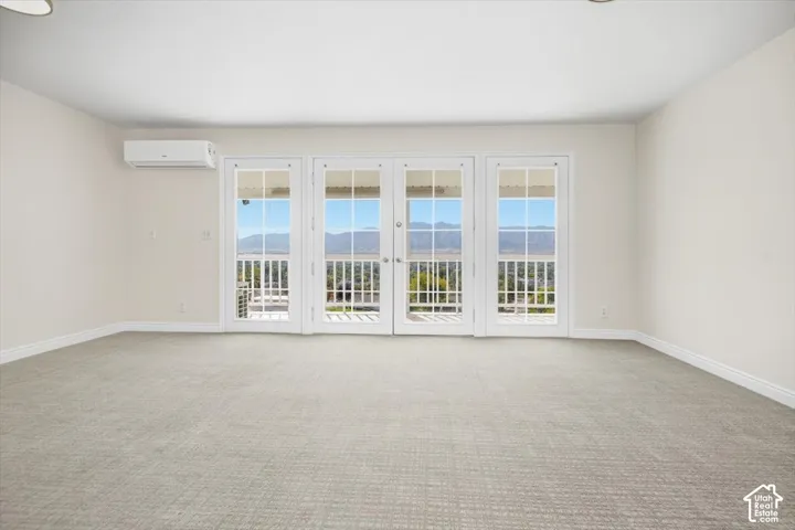 Light-toned carpeting and neutral wall tones complement the bright space, which features multiple French doors leading to an exterior balcony