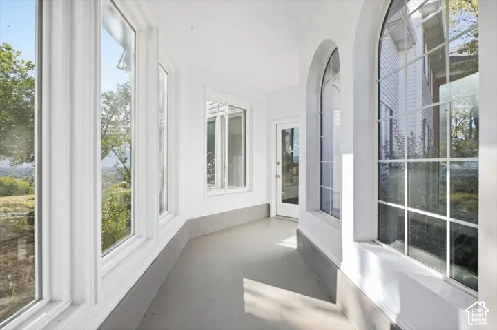 Curved porch with white walls, arched windows, and multiple clear-pane windows