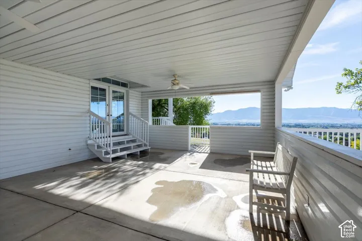 Covered patio with concrete flooring, dual French doors, and a ceiling fan