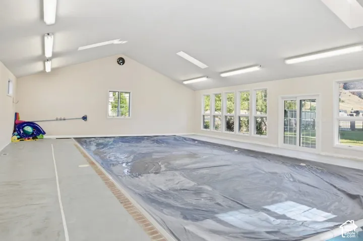 Indoor swimming pool with an angled ceiling, multiple windows, and a sliding glass door