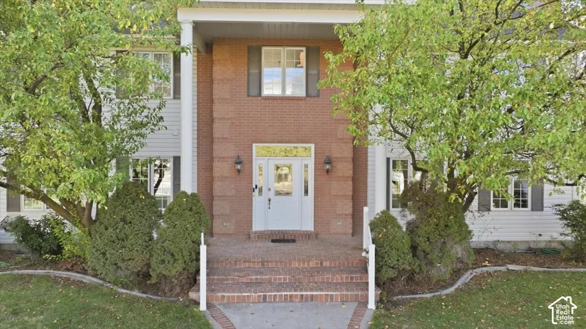 Brick and siding exterior with a prominent front entrance, white paneled door, and side lights