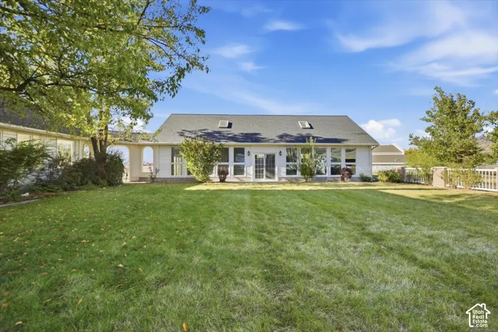 Expansive green lawn, white exterior siding, arched architectural detail, multiple windows, and a dark shingle roof