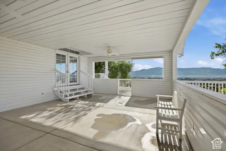 Covered patio featuring a concrete surface, white siding, and a ceiling fan