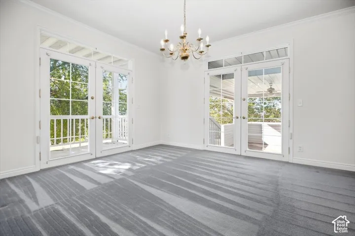 Light-filled room featuring two sets of double French doors with transom windows, a central chandelier, and patterned carpeting