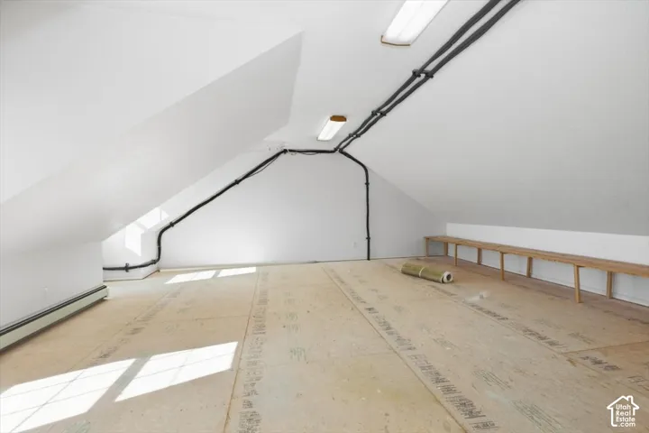 Vaulted ceilings with exposed conduit, unfinished wood subflooring, and a built-in wooden bench