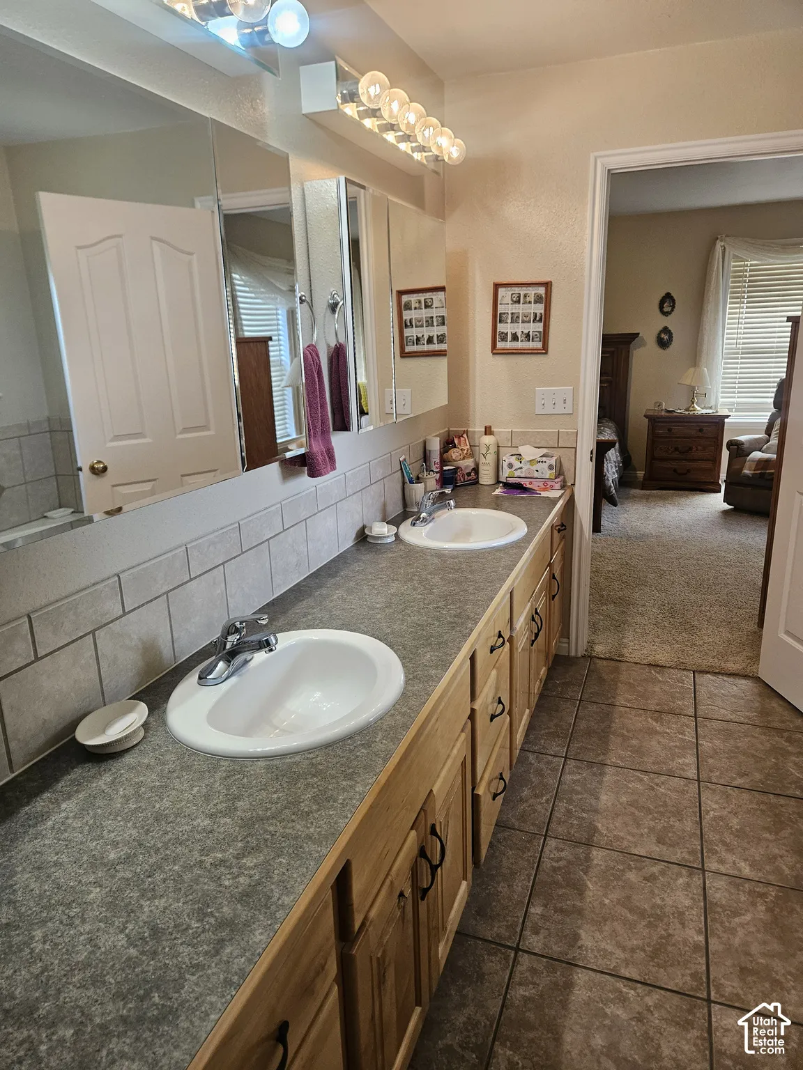Dual vanity with integrated sinks, wood-finish cabinetry, and a full-width mirror