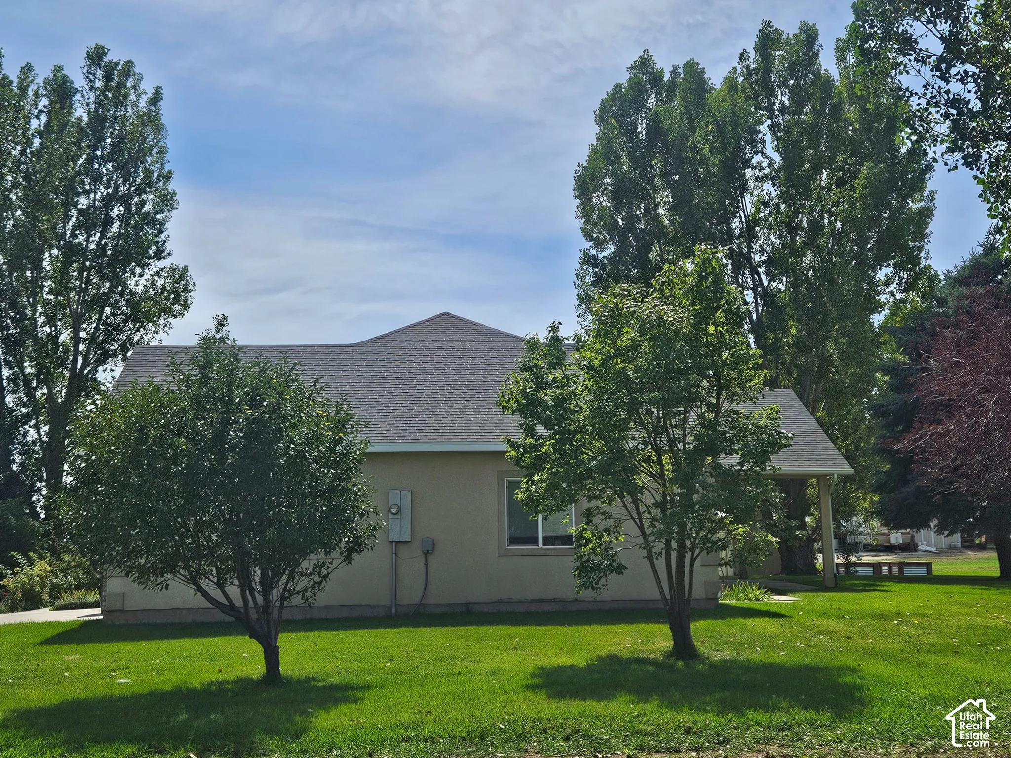 Single-story residence featuring a gray shingle roof, stucco exterior, and a covered porch