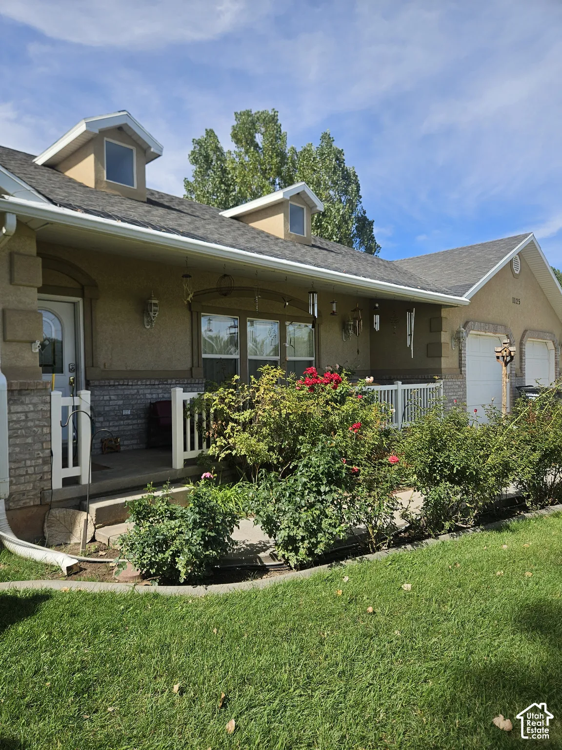 Dormer windows, attached garage, covered front porch, and mature landscaping