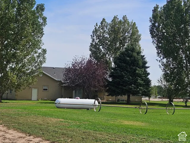 Spacious green lawn with mature trees and a tan exterior residence