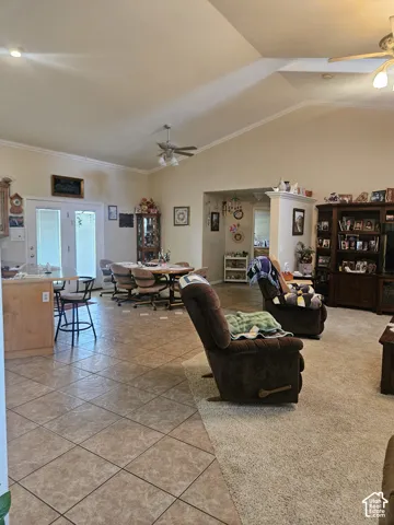 Vaulted ceilings with ceiling fans, crown molding, tile flooring, and a kitchen island with built-in cabinetry