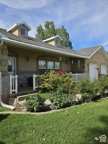 Dormer windows, attached garage, covered front porch, and mature landscaping