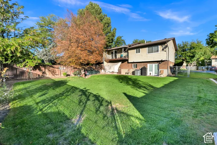 Expansive grassy yard with mature trees and a wood fence