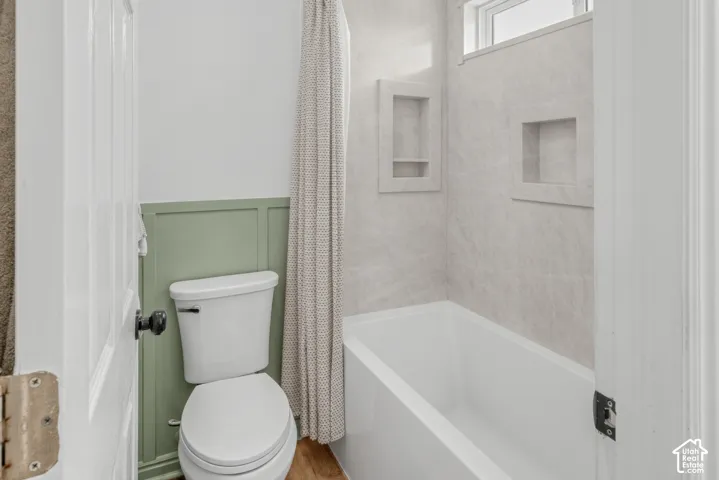 Bathtub with integrated shelving, tile-style surround, and transom window