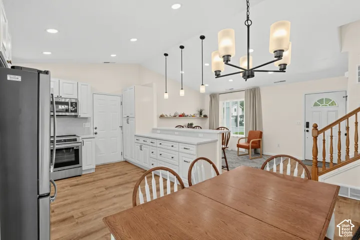 Kitchen featuring white cabinetry, stainless steel appliances, a center island with countertop seating, and wood-finish flooring