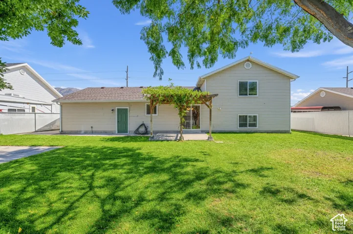 Expansive lawn with a two-story exterior, attached concrete patio, and a wood pergola