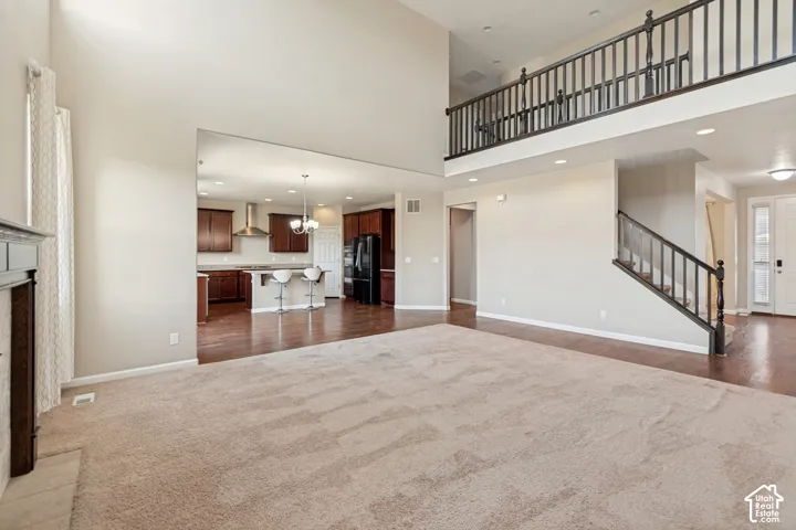 Vaulted ceilings, wood-finish flooring, two-story great room, kitchen with dark wood cabinetry, and a carpeted main living area