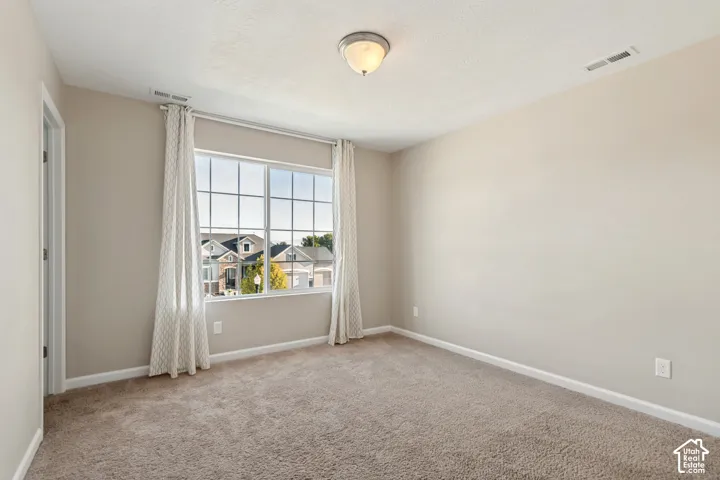 Carpeted room with a large window and neutral wall paint