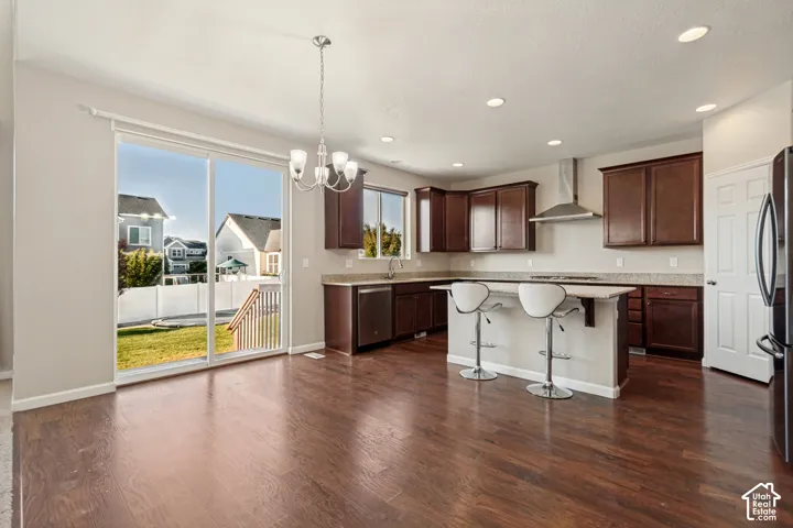 Open-concept kitchen and dining area featuring rich wood-finish flooring, dark wood cabinetry, and a center island with countertop seating