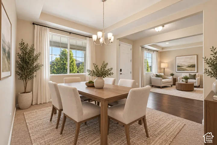 Tray ceiling with a chandelier, large multi-pane window, and a cased opening to a separate room with wood-finish flooring
