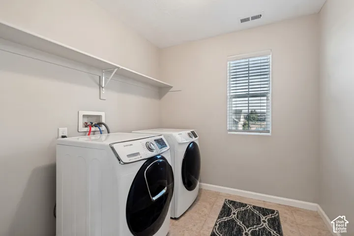 Utility room featuring a window with blinds, tile flooring, and wall-mounted shelving