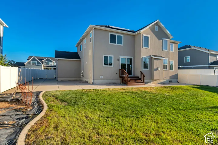 Expansive backyard featuring a lush lawn, concrete patio, and privacy fencing