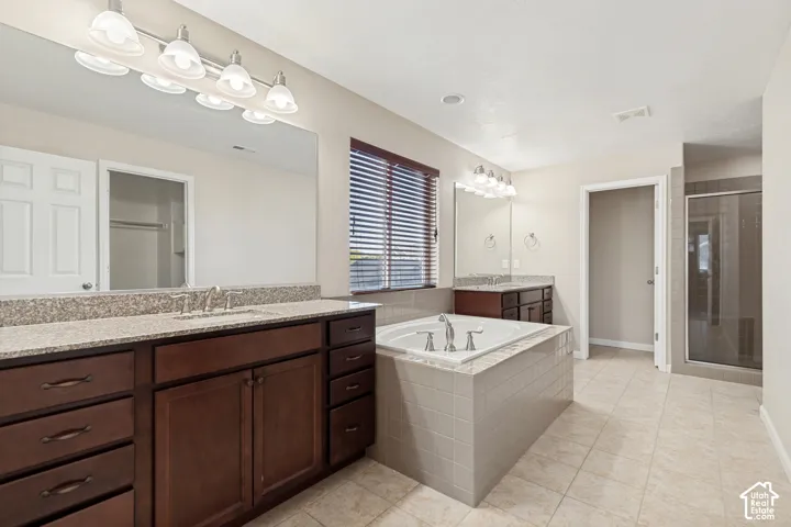 Dual vanity with granite countertops, a built-in soaking tub, a separate glass-enclosed shower, and tile flooring