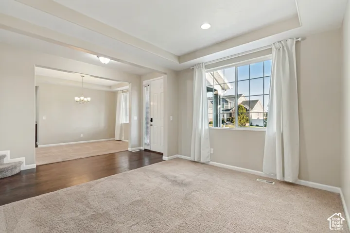 Recessed lighting, large window with grid pattern, neutral-toned carpet flooring, dark wood-finish flooring, and tray ceiling detail