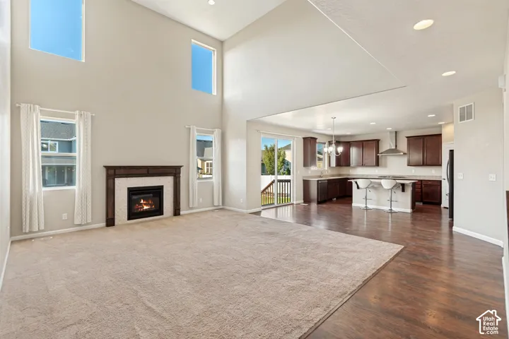Vaulted ceilings with high windows, fireplace with wood surround, dark wood-finish flooring, dark wood cabinetry, and stainless steel appliances