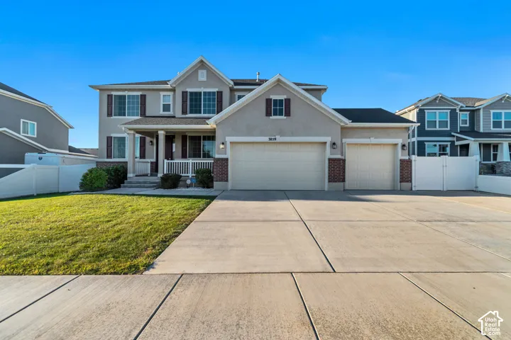 Two-story stucco exterior with brick accents, covered front porch, integrated three-car garage, and concrete driveway