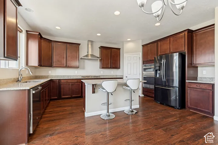 Kitchen featuring wood-finish flooring, wood cabinetry, stone countertops, and built-in stainless steel appliances