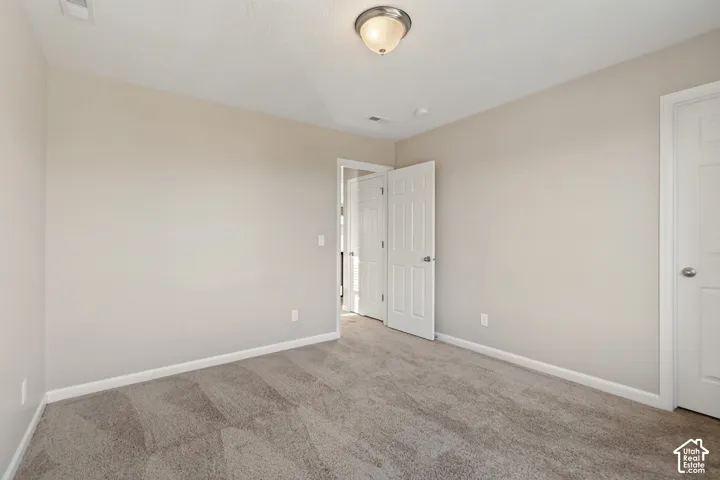 Neutral tone wall paint, flush mount ceiling light fixture, panel interior doors, and carpet flooring