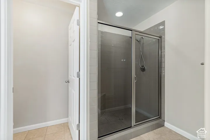 Glass-enclosed shower with a handheld shower head, tiled walls, and a built-in bench