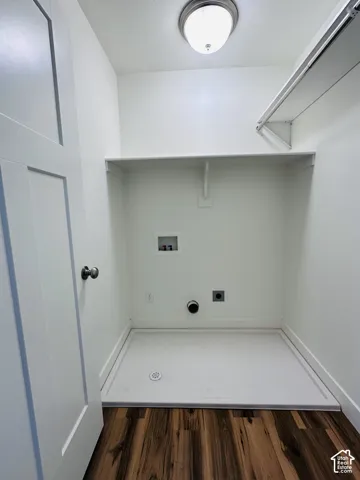 Utility room featuring wood-finish flooring, built-in shelving, and a white laundry pan