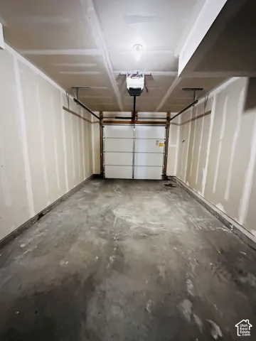 Single-car garage featuring a roll-up garage door and overhead lighting