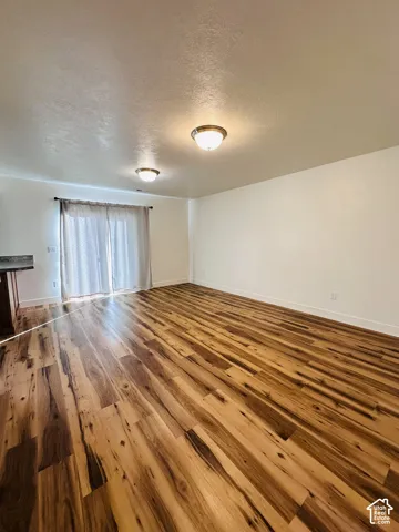 Wood-finish flooring throughout, bright white walls, and a sliding glass door with privacy drapery