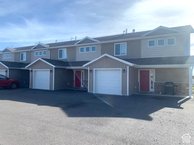 Multi-unit property featuring tan siding, red entry doors, and attached garages