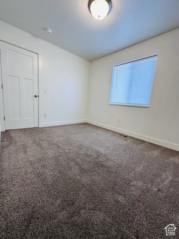 White paneled interior door, flush-mount ceiling light fixture, window with blinds, and neutral-toned carpet
