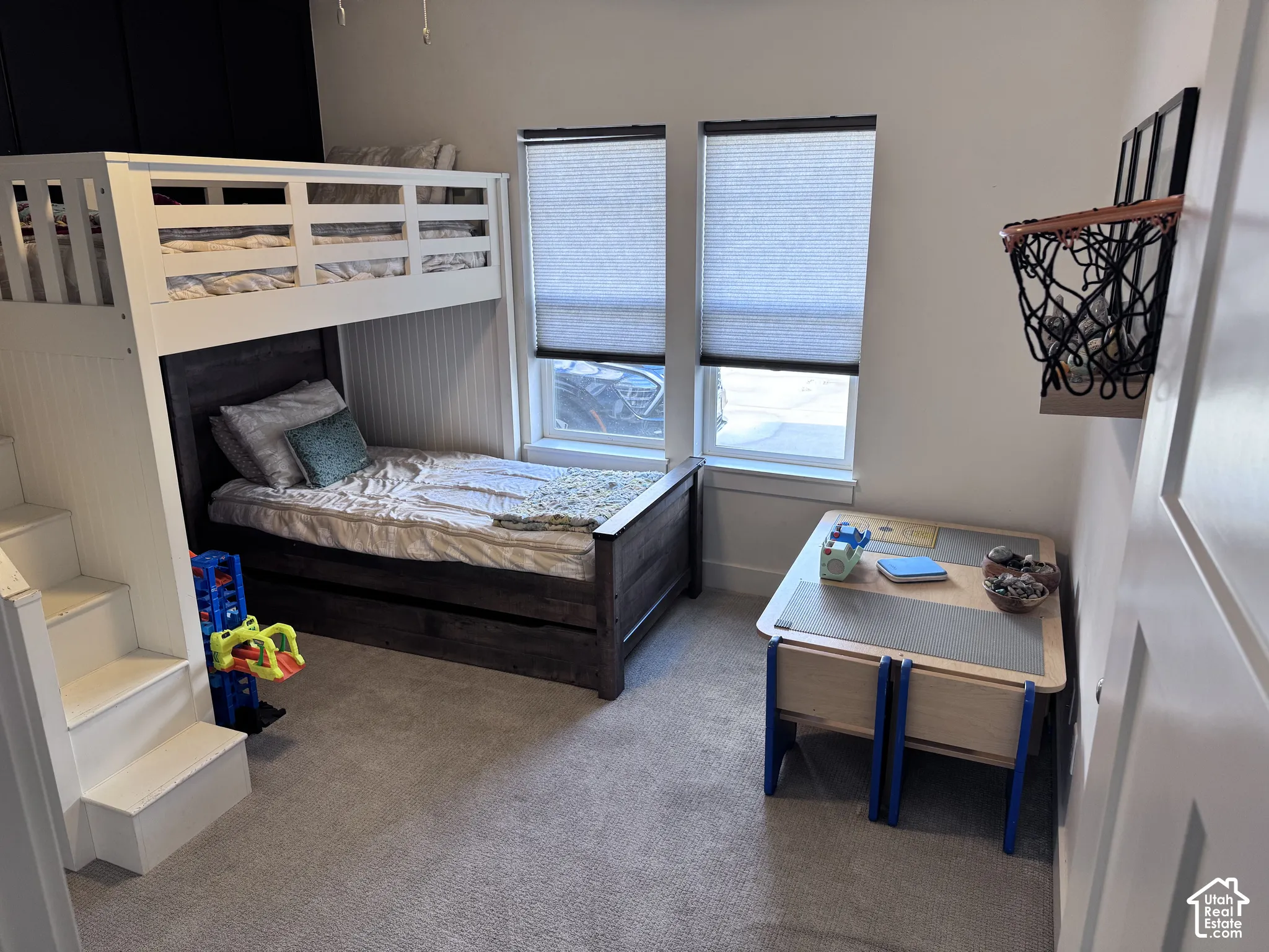 Bedroom featuring carpeted flooring, two windows with blinds, and white beadboard wall accents