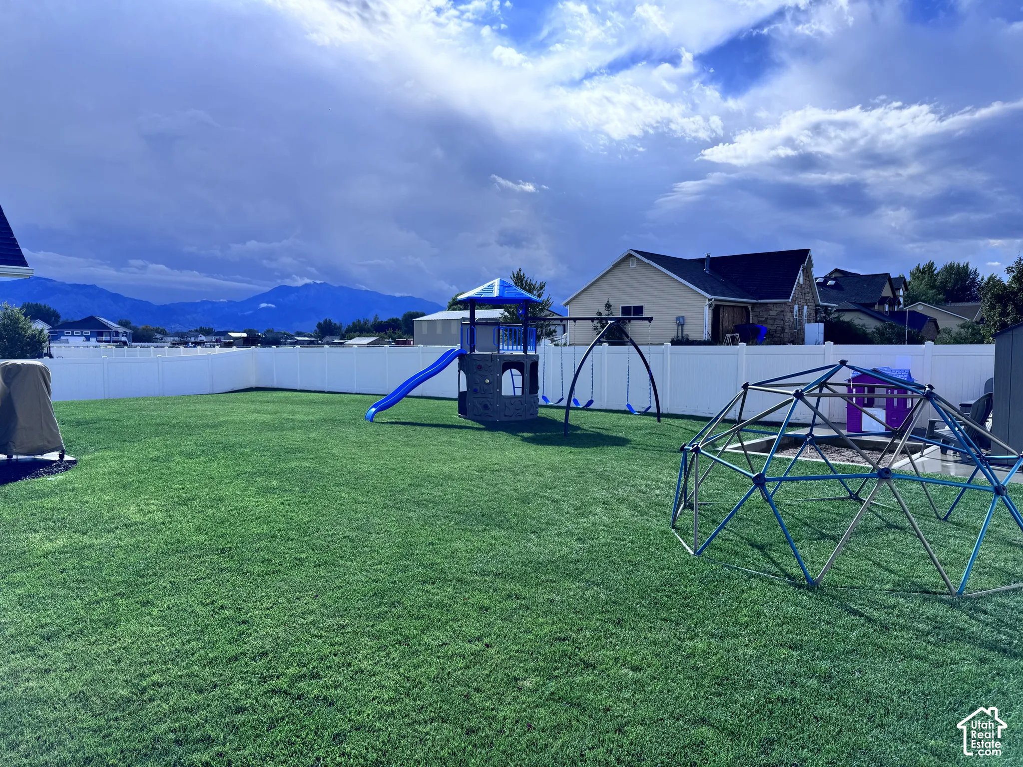 Expansive green lawn, white privacy fencing, and distant mountain scenery