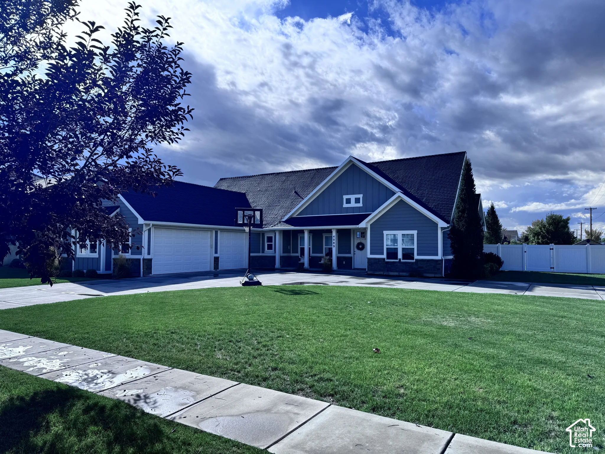 Exterior featuring a dark shingle roof, blue siding, white window trim, and a white garage door