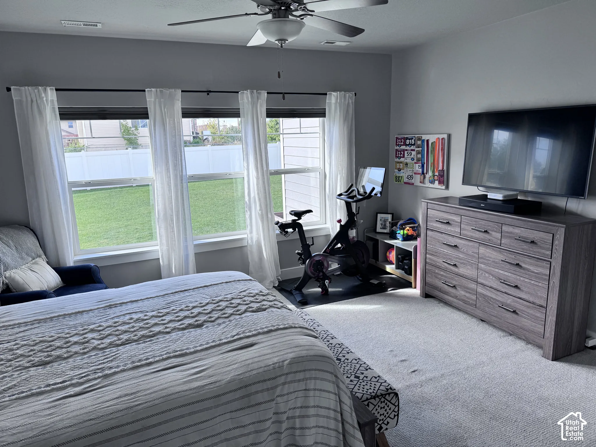 Multiple windows providing natural light, overhead ceiling fan, light-toned wall paint, and carpeted flooring