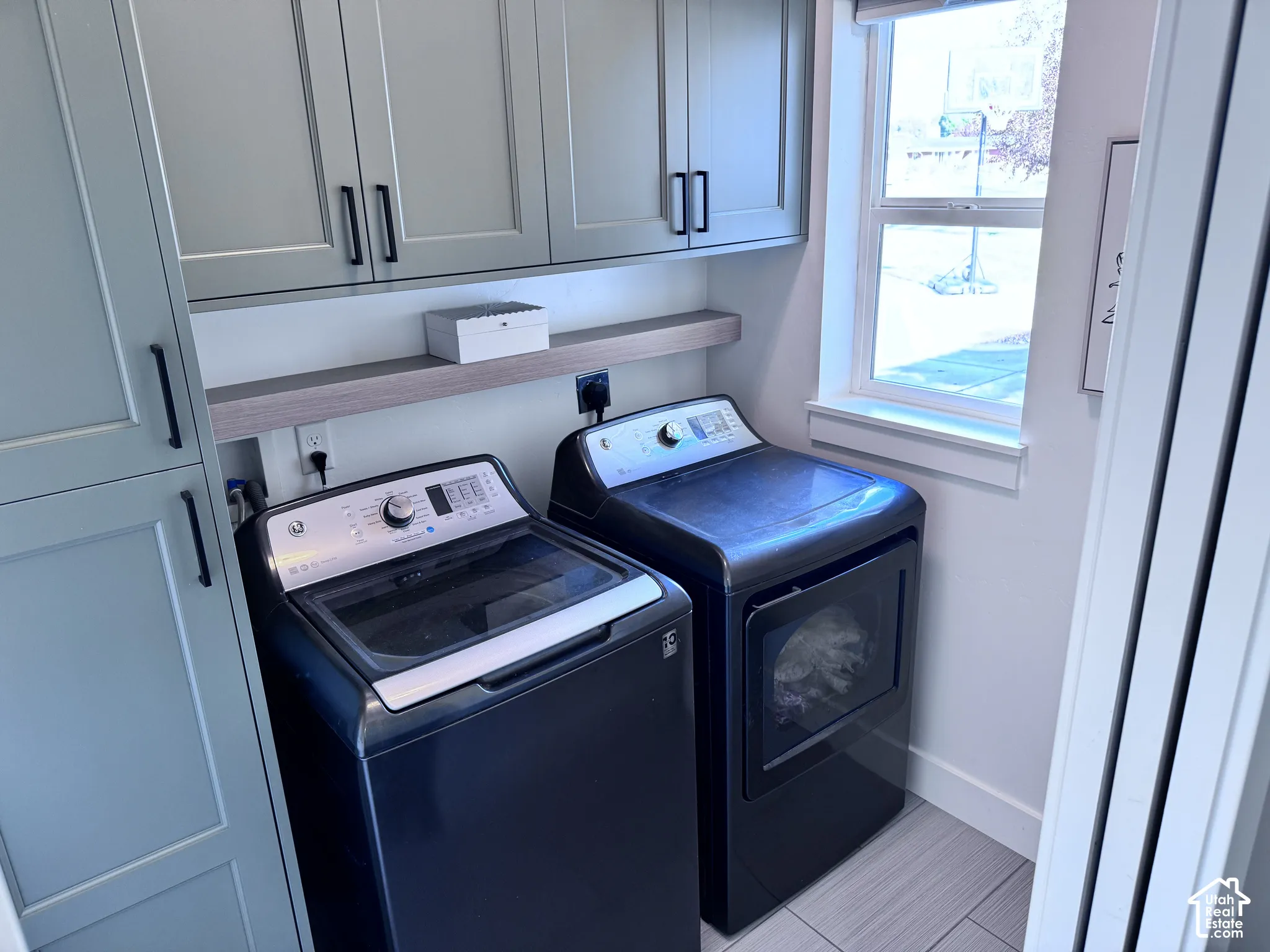 Built-in cabinetry with matte black hardware, floating wood-finish shelving, and a single pane window