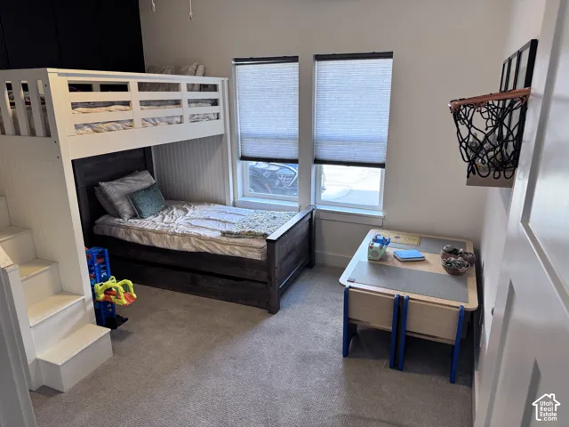 Bedroom featuring carpeted flooring, two windows with blinds, and white beadboard wall accents