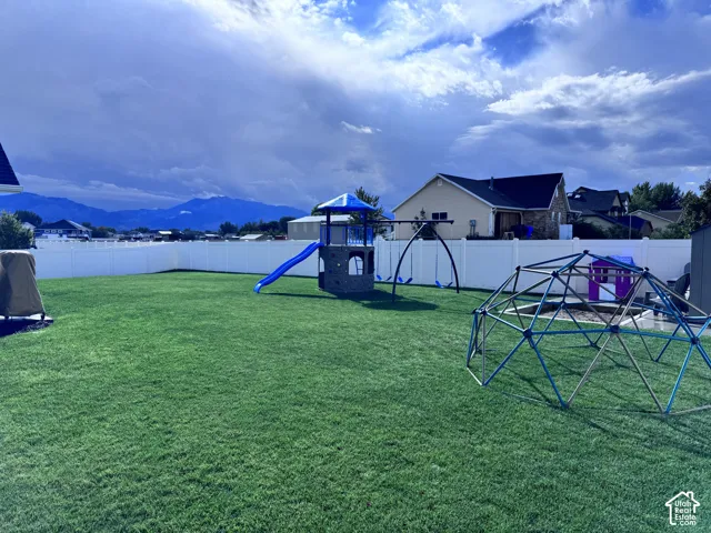 Expansive green lawn, white privacy fencing, and distant mountain scenery