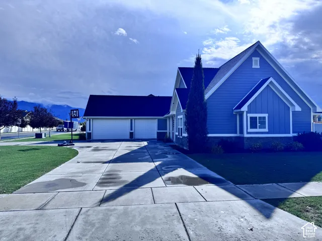 Blue siding exterior with white trim, a dark shingle roof, a two-car garage, and a concrete driveway
