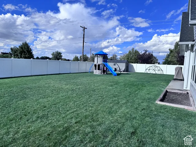 Expansive rear yard featuring a privacy fence, manicured lawn, and a small concrete patio