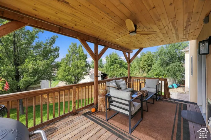 Covered wood-finish deck with a ceiling fan, a wood ceiling, and wood railings